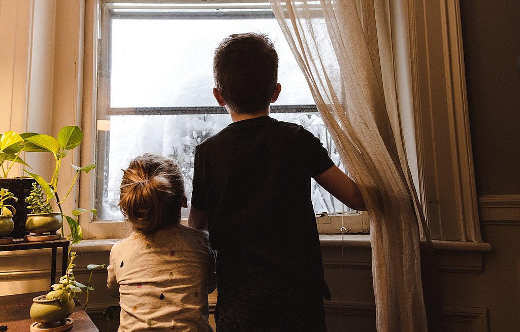 Zwei Kinder von hinten aufgenommen schauen aus dem Fenster