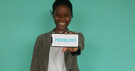 Eine People of Color Frau hält ein Handy vor sich auf dessen Bildschirm "Possibilities" steht