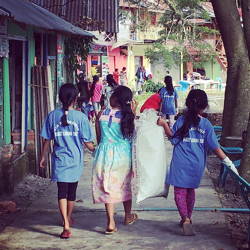 drei Kinder von hinten fotaografiert mit Säcken voller Plastikmüll