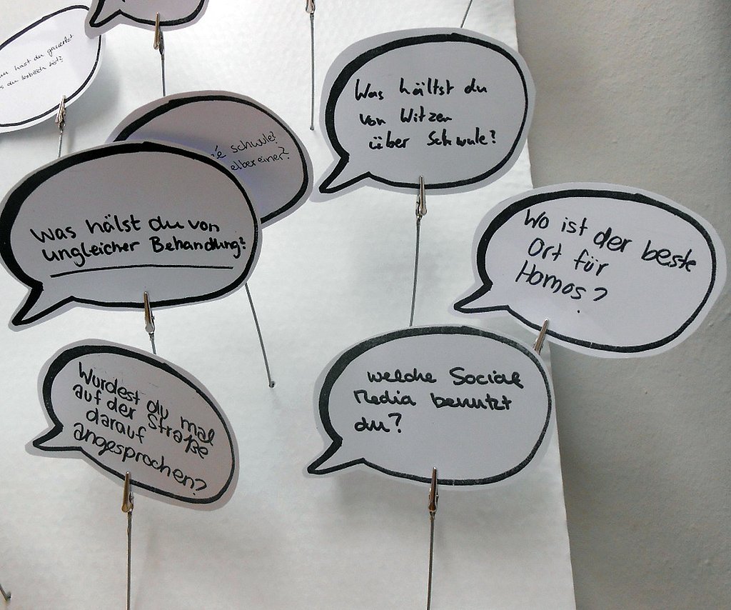 Fragen von Kindern und Jugendlichen an Homosexuelle auf gebastelten Sprechbalsen aus Papier