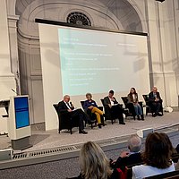 Das Foto zeigt Menschen auf einem Podium, unter anderem Prof. Dr. Heidi Höppner als Podiumsmitglied.