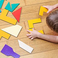 Ein kleiner Junge liegt auf dem Boden und spielt mit geometrischen Formen
