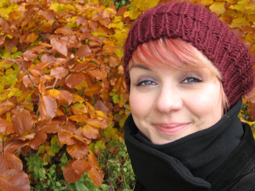 Porträt von Katja Bilieg mit Mütze vor gelben Herbstlaub
