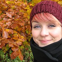 Porträt von Katja Bilieg mit Mütze vor gelben Herbstlaub