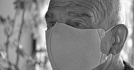 Schwarz-Weiß-Bild: Kopf eines alten Mannes mit Maske auf