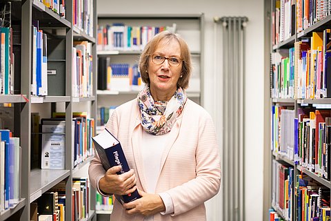 Das Foto zeigt Prof.in Dr.in (i.R.) Gudrun Piechotta-Henze in einer Bibliothek.