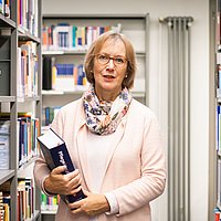 Das Foto zeigt Prof.in Dr.in (i.R.) Gudrun Piechotta-Henze in einer Bibliothek.
