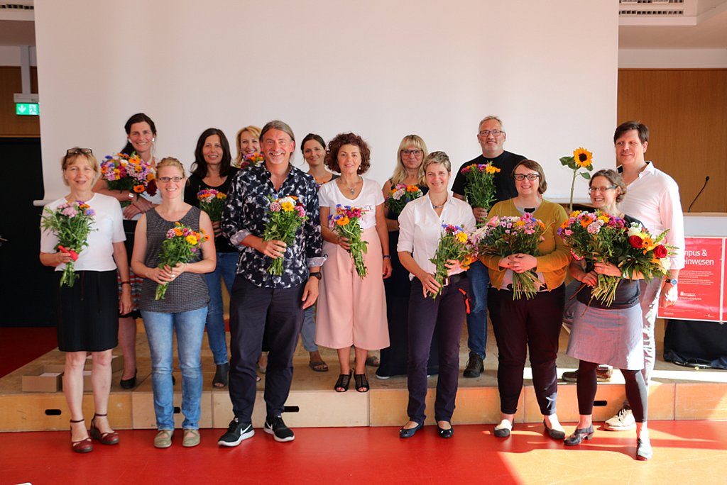 Mitwirkende des Projekts mit Blumenträußen in den Händen