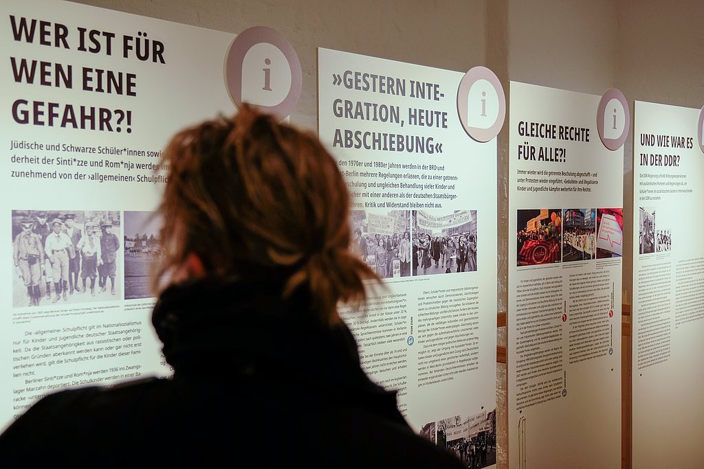 Besucherin von hinten schaut sich Plakate bei der Ausstellungseröffnung an