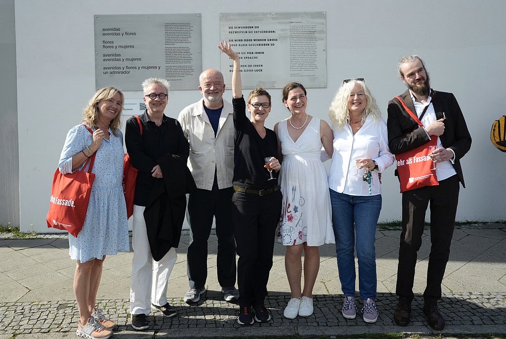 Maxi Obexer, die Jury des Alice Salomon Poetik Preises und Jörg van den Berg vor der Fassade der Hochschule, im Hintergrund die Gedenktafeln mit den Werken von Eugen Gomringer und Barbara Köhler