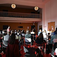 Die Teilnehmenden der Tagung sitzen im Audimax der ASH Berlin und unterhalten sich.