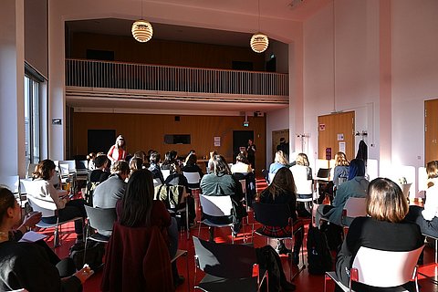 Die Teilnehmenden der Tagung sitzen im Audimax der ASH Berlin und unterhalten sich.