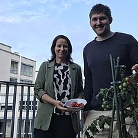 Two employees show harvested tomatoes.