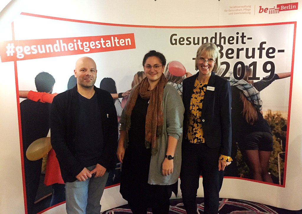 die drei Personen stehen vor einem Banner des Berufe-Tags