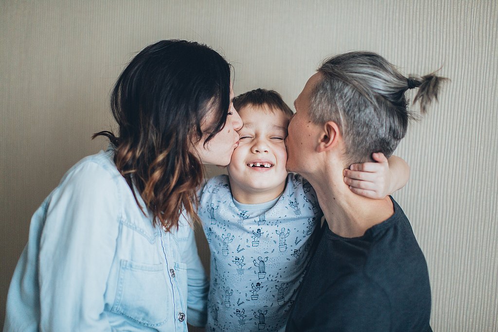 Ein Kind in der Mitte von seinen Eltern, die es küssen