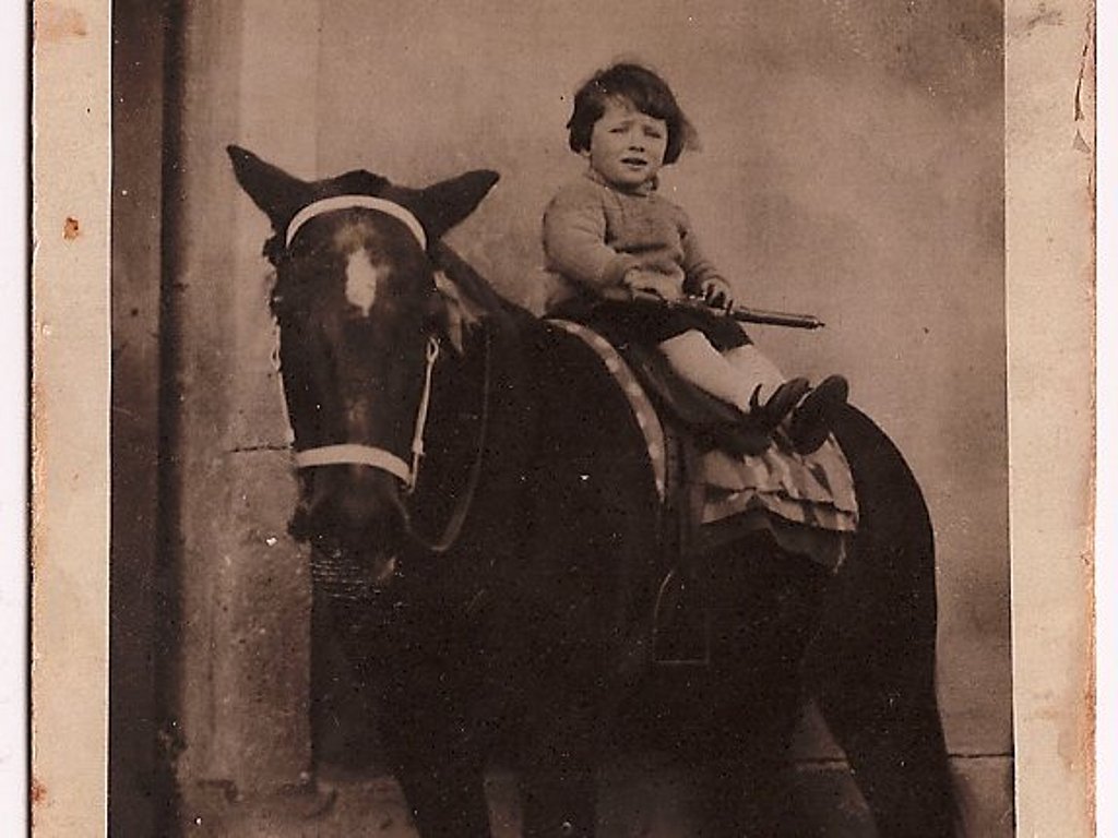 Ein kleines Mädchen sitzt auf dem Rücken von einem Pferd - Schwarz-Weiß Fotografie