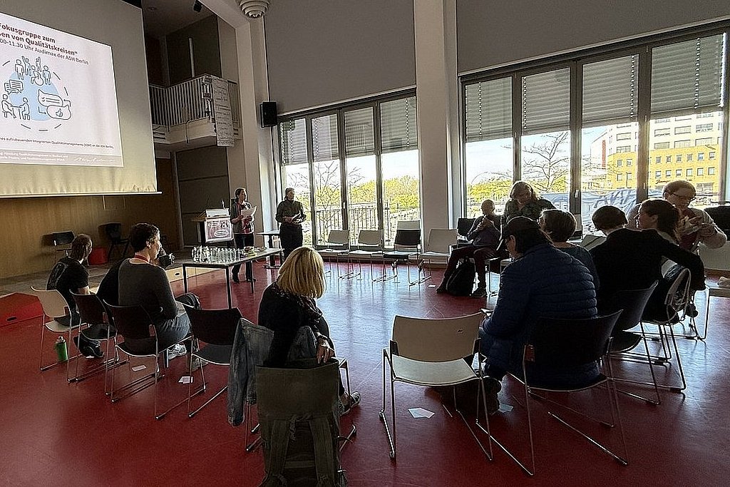 Angehörige der ASH Berlin sitzen in einem Kreis im Audimax der Hochschule und diskutieren miteinander