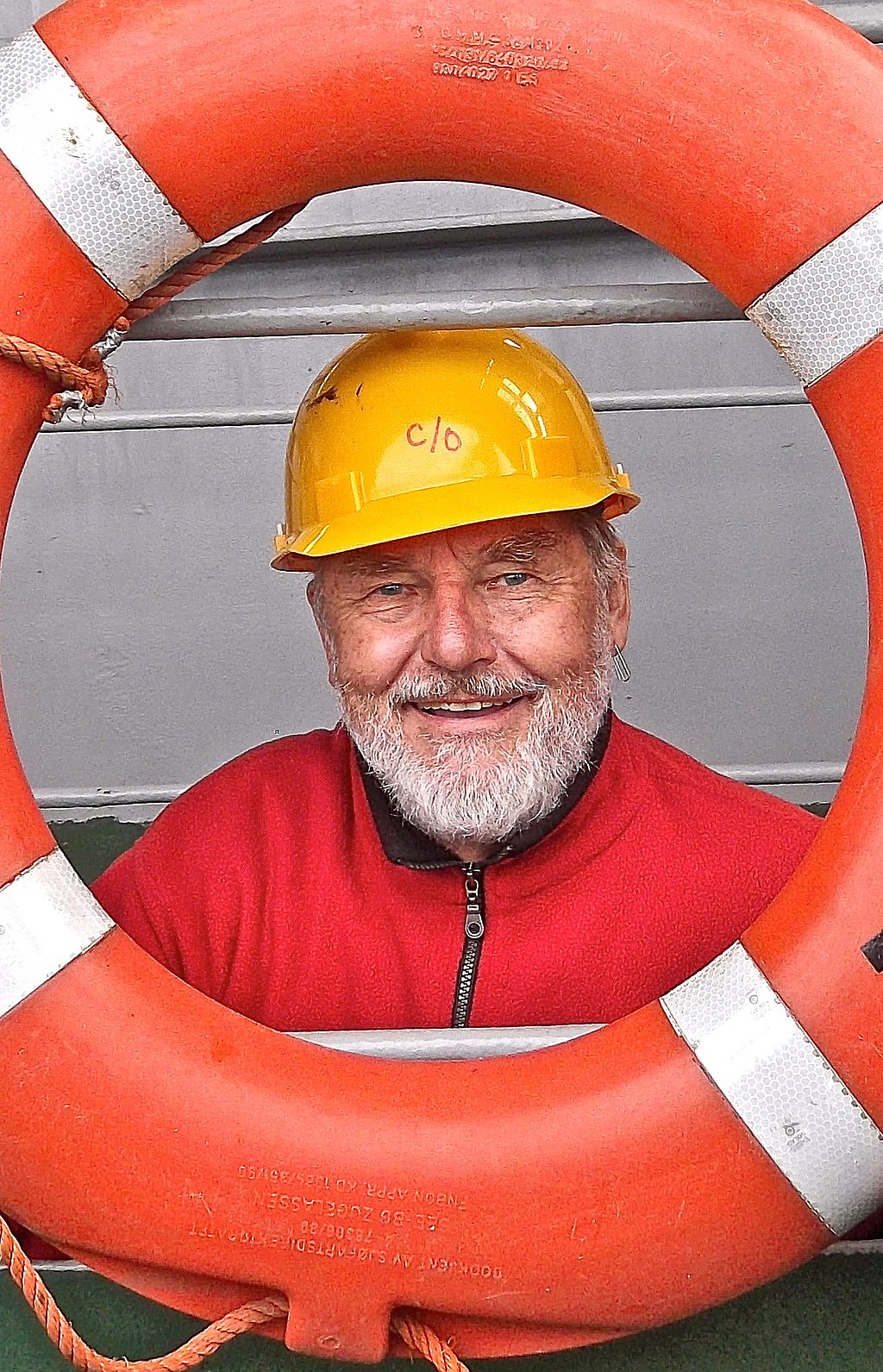 Joachim Wieler mit einem gelben Sicherheitshelm auf dem Kopf schaut durch einen Rettungsring