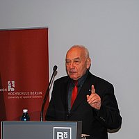 Eugen Gomringer steht hinter einem Rednerpult und spricht zum Publikum