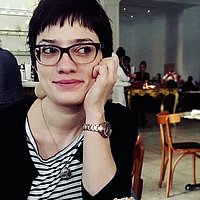 Porträt von Katja Schatte, die Hand auf das Kinn gestützt, mit Brille