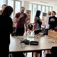 Tagungsteilnehmer_innen stehen in der Hochschullernwerkstatt Kommunikation und Sprache an der ASH Berlin und unterhalten sich