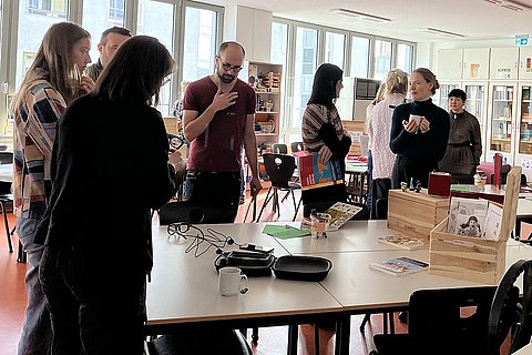 Tagungsteilnehmer_innen stehen in der Hochschullernwerkstatt Kommunikation und Sprache an der ASH Berlin und unterhalten sich