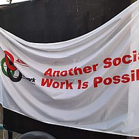 Eine weiß Fahne mit roter Aufschrift "another social work is possible"