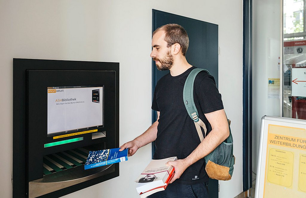 Ein Student gibt Bücher in den neuen Rückgabeautomat