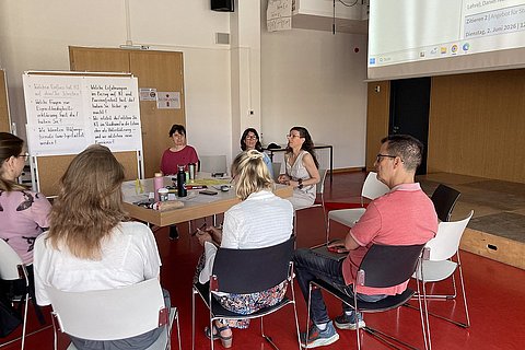 Personen sitzen im Audimax an einem großen Tisch und diskutieren 