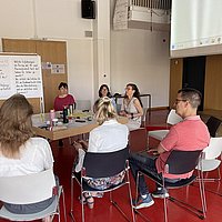 Personen sitzen im Audimax an einem großen Tisch und diskutieren 