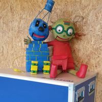 Die Forschergeister Helle und Leum auf einer Tüfteltruhe