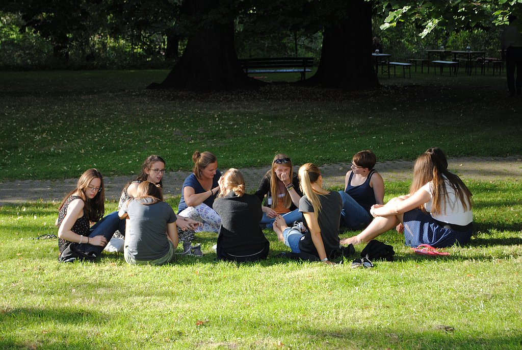 Studentinnen sitzen im Kreis auf einer Wiese