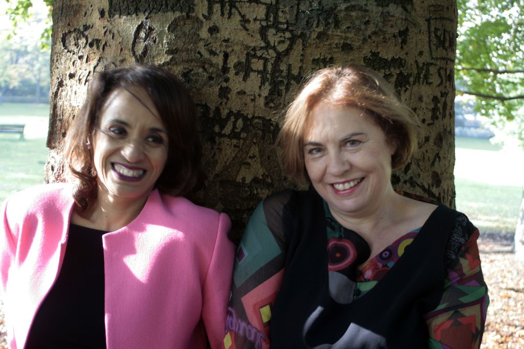 Vergrößern: Susanne Diehm und Jutta Michaud sitzen an einen Baum angelehnt im Grünen.