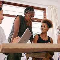 vier junge Menschen unterschiedlicher Hautfarbe diskutieren an einem Tisch