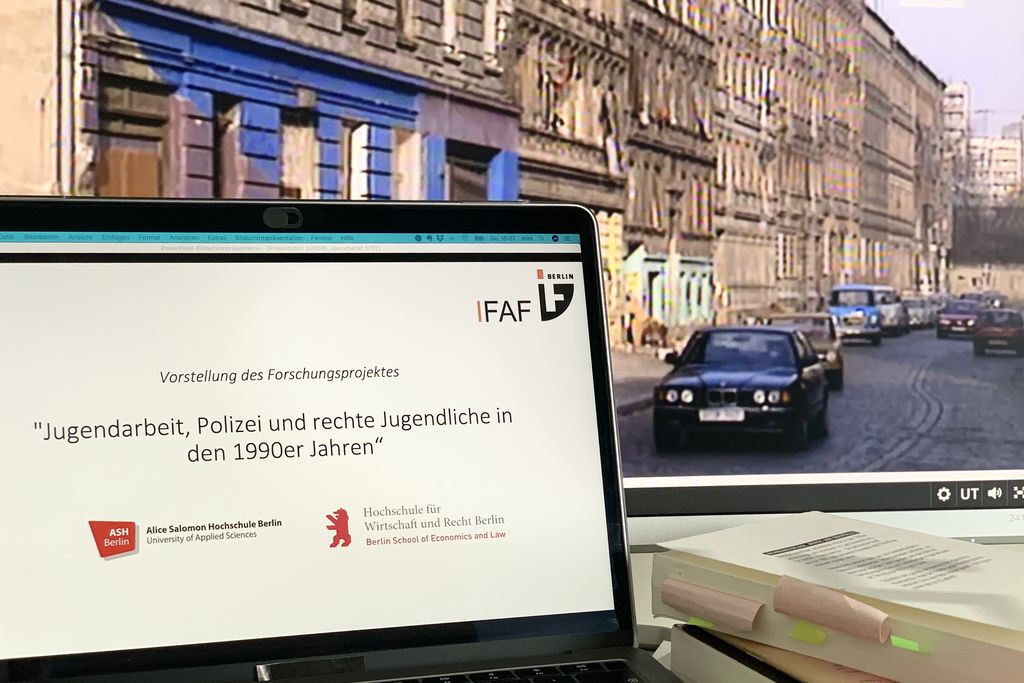 Vergrößern: Ein Laptop auf dessen Bildschirm der Projektname steht, rechts daneben ein Bücherstapel