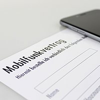 Ansicht eines Mobilfunkvertrag-Formulares, daneben liegt ein Smartphone