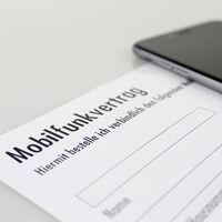 Ansicht eines Mobilfunkvertrag-Formulares, daneben liegt ein Smartphone