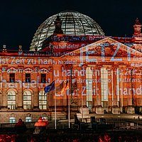 Reichstag angestrahlt mit einer Schriftbotschaft