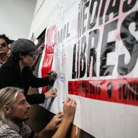 Ein Plakat vor dem Menschen stehen und Andrea Plöger mit Mütze unterzeichnet darauf