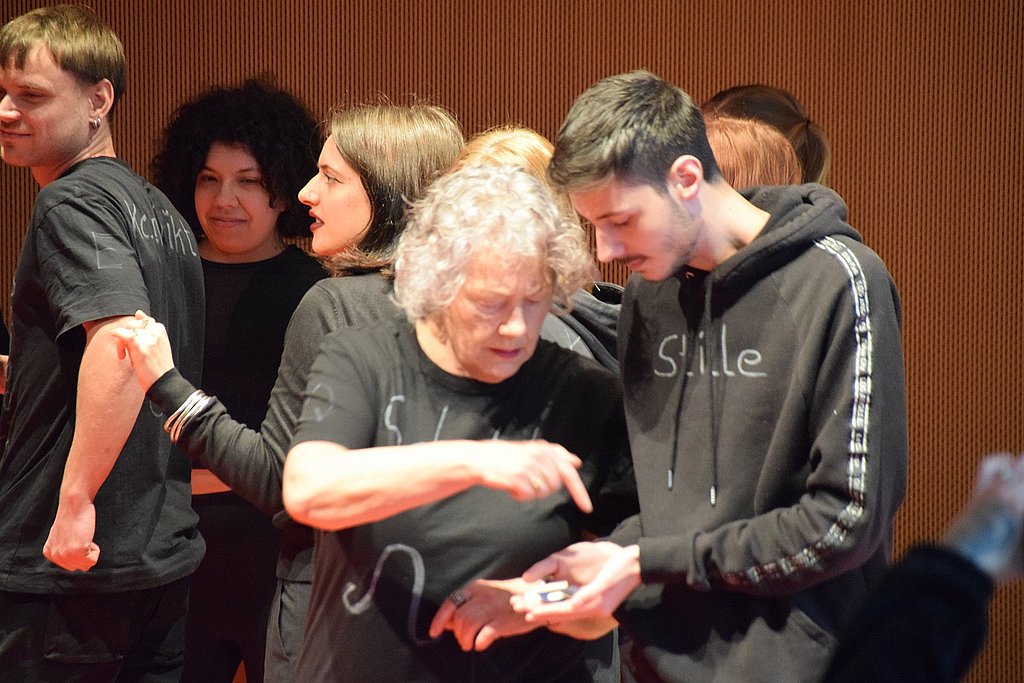 A group of older and younger people perform a play.