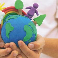 Cover der Broschüre Kimawandel begreifen - Kinderhände halten eine Edkugel aus Knete