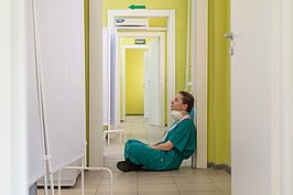 Erschöpfte Pflegende sitzend auf dem Krankenhausflur