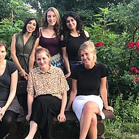 Mehrere Frauen auf einer Gartenbank in einem Garten