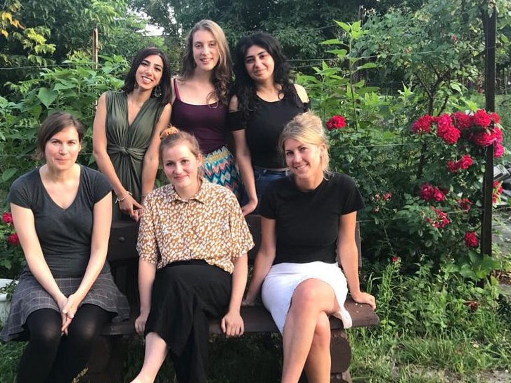 Mehrere Frauen auf einer Gartenbank in einem Garten
