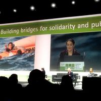 Eine große Leinwand, davor Zuhörer_innen und die Vortragende