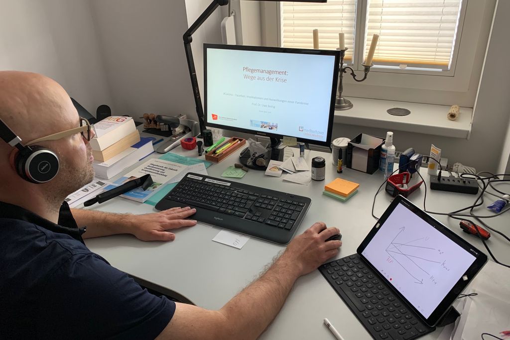 Vergrößern: Uwe Bettig an seinem Schreibtisch vor dem Computer und mit Kopfhörern auf den Ohren