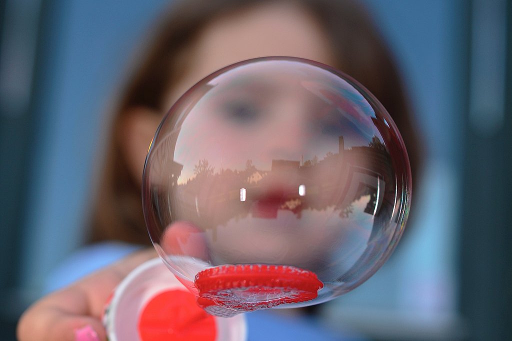 im Vordergrund eine Seifenblase, dahinter verschwommen ein Kindergesicht