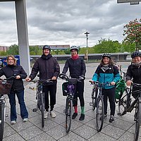 Foto von fünf Fahrradfahrenden vor dem Hauptgebäude der ASH Berlin