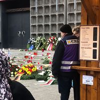 Ein Mann mit einer Weste von PSNVNET steht vor der Treppe der Gedächtniskirche mit Kerzen auf dem Boden